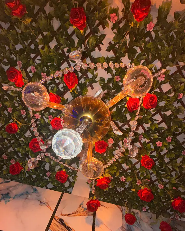 Techo de rosas y enrejado verde con lámpara de cristal