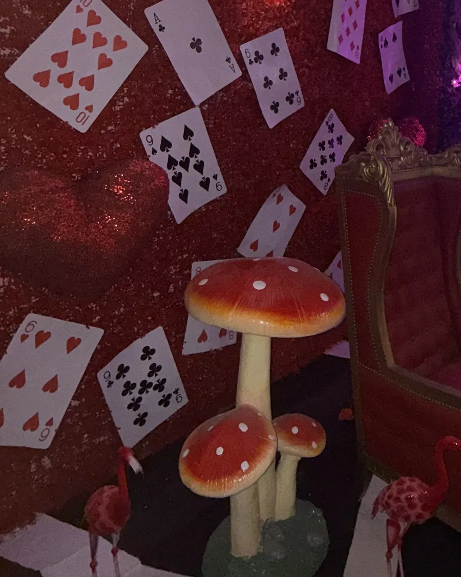 Pared de naipes con hongos rojos y un sillón de terciopelo